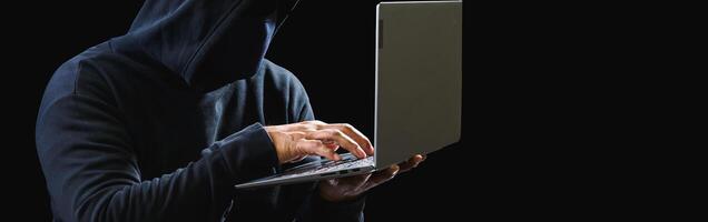 Hacker spy man one person black hoodie sitting hand holding credit card look computer laptop used login password attack security data digital internet network system night dark background copy space photo