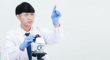 Portrait asian man student scientist wearing a doctor gown in the lab looking hand at chemist. caused by mixing reagents in scientific research laboratories with test tubes and microscope on the table photo