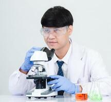Portrait asian man student scientist wearing a doctor gown in the lab looking hand at chemist. caused by mixing reagents in scientific research laboratories with test tubes and microscope on the table photo