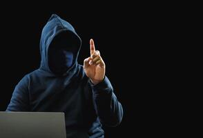 Hacker spy man one person black hoodie sitting hand holding credit card look computer laptop used login password attack security data digital internet network system night dark background copy space photo