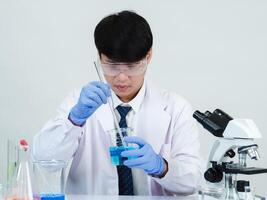 Portrait asian man student scientist wearing a doctor gown in the lab looking hand at chemist. caused by mixing reagents in scientific research laboratories with test tubes and microscope on the table photo