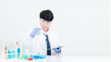 Portrait asian man student scientist wearing a doctor gown in the lab looking hand at chemist. caused by mixing reagents in scientific research laboratories with test tubes and microscope on the table photo