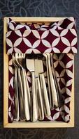 Top View of Silver Cutlery Set in Wooden Box with Patterned Fabric Lining on Textured Surface photo