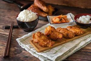 Closed up Korean food on wooden background, kimchi soup and fried chicken with source, garlic, spicy and steamed rice photo