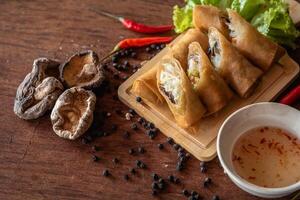 Chinese vegetable spring rolls with chopstick to dip in sauce on wooden background photo