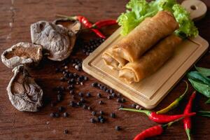 Chinese vegetable spring rolls with chopstick to dip in sauce on wooden background photo