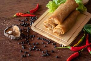 Chinese vegetable spring rolls with chopstick to dip in sauce on wooden background photo