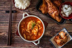 Top view Korean food on wooden background, kimchi soup and fried chicken with source, garlic, spicy and steamed rice photo