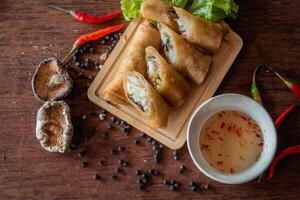 Chinese vegetable spring rolls with chopstick to dip in sauce on wooden background photo