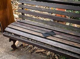 smartphone left on a dirty city park bench with lots of rubbish photo