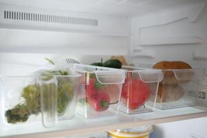 plastic containers with different fruits in a open fridge. photo