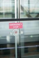 An emergency stop button is placed on a glass wall in a public space for safety measures photo