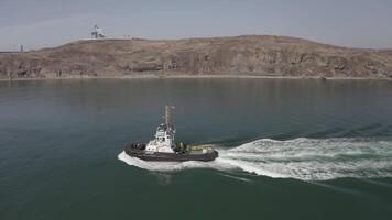Aerial view of a tugboat in motion. Drone captures the action video
