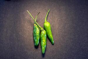 Three green cayenne pepper with very spicy taste isolated on dark background photo