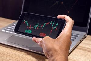 A man's hand using a smartphone to analyze stock market, cryptocurrency or trading data charts. Risk management in trading concept. photo