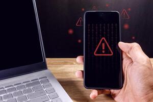 Man holding a smartphone with red triangle caution warning sign for notification error, restricted content or maintenance concept photo