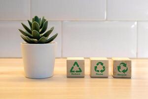 Artificial flower in a pot and wooden blocks with reduce, reuse, recycle symbol. Environmental concept. photo