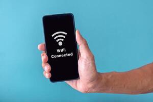 Hand holding a smartphone with WiFi icon on screen. Connecting smartphone to Wifi. Wifi internet access concept. photo