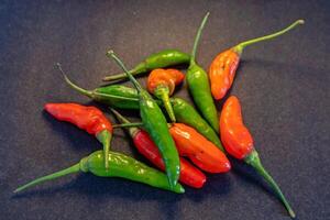 Pile of red and green cayenne pepper isolated on dark background photo