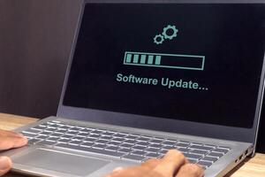 A laptop on the table with updating progress bar on screen. Software system update process concept. photo