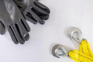 A pair of black safety work gloves and yellow tow rope with hooks on a white background photo