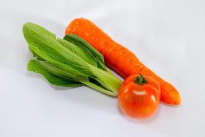 Fresh vegetables on white background. Carrot, tomato, and pak choi cabbage. photo