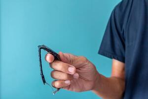 Man holding an analog watch to check the time on a blue background photo