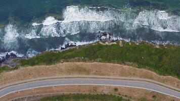 View from a drone vertically down on an empty asphalt road along the coast video