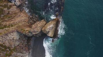 Aerial view by drone 4k camera. Ocean with waves and rocky cliff. Zoom in video