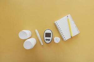 top view of diabetic measurement tools and pills container on color background photo
