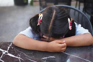 A girl with pigtails rests on a marble table, showing a serene moment of contemplation photo