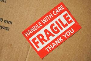 A cardboard box marked with a caution label for fragile goods handling during shipping photo