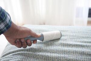 using an adhesive roller to remove lint and fluff from a bed . photo