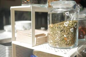 A detailed view of various jars filled with herbs and spices in a warm kitchen or cafe atmosphere photo