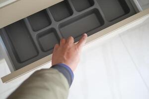 Hand opens drawer with empty organizing tray to maintain neat order in the space photo