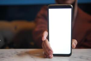 Person holds smartphone with blank screen on table, symbolizing modern technology photo