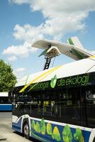An electric bus stands at an empty bus stop and charges, a close up photo