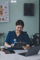 Female doctor writing in a notebook and holding a medicine bottle works at a computer while there were many medicine bottles on the table while sitting at a work desk photo