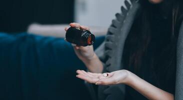 A woman with a cold with pills is treated at home chooses which drugs to take and self-medicates, checks the expiration date while sitting on the couch at home photo