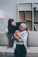 Adult daughter old mom hugging sit on couch enjoy pleasant positive talk, remembering funny occasion from life spend weekend together, caring about older generation relatives express attention concept photo