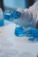 Group of dedicated scientist conduct chemical experiment in medical laboratory, carefully drop precise amount of liquid from pipette into test tube for vaccine drug or antibiotic development. Neoteric photo