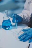 Group of dedicated scientist conduct chemical experiment in medical laboratory, carefully drop precise amount of liquid from pipette into test tube for vaccine drug or antibiotic development. Neoteric photo