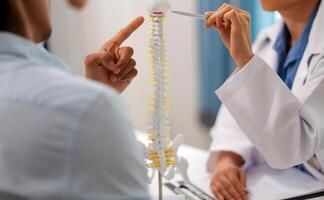 Orthopedists holding digital tablet and pointing at model. Concept of osteoporosis, back pain, lumbar, chiropractic and health. photo