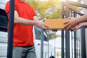 Asian delivery express courier young man use giving boxes to woman customer he wearing protective face mask at front home photo