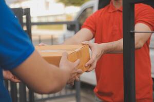 Asian delivery express courier young man use giving boxes to woman customer he wearing protective face mask at front home photo