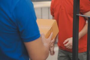 Asian delivery express courier young man use giving boxes to woman customer he wearing protective face mask at front home photo