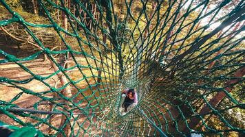 HBH adventure park, Palanga, Lithuania -2023 - woman use safety net in adventure park climb net up to platform. Exercise in the woods. Adventure parks extreme sports in Lithuania photo