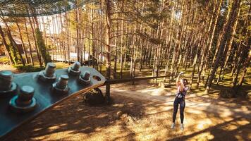 Palanga, Lithuania - 2023 - young woman girl sliding along zipline in fir tree forest in summer. Lithuania adventure park in HBH. photo