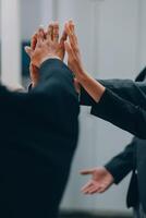 Motivated successful business team giving high five, happy young students employees group join hands with senior teacher mentor, team building unity concept, help support in teamwork, close up view photo