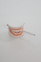 Ashtray in the form of a tooth with a stub on a white background photo